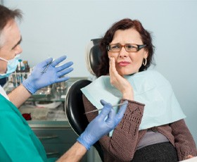 A senior dentist trying to help a woman with a toothache