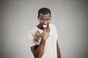 man pointing to his mouth with his tongue out