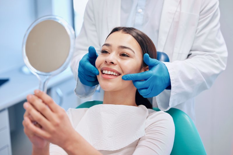 a young woman admiring her smile at the dentist’s office